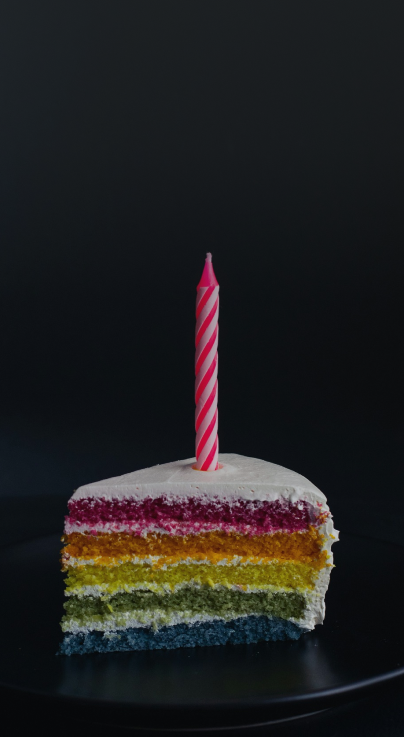 foto de uma fatia de bolo de aniversário com uma vela